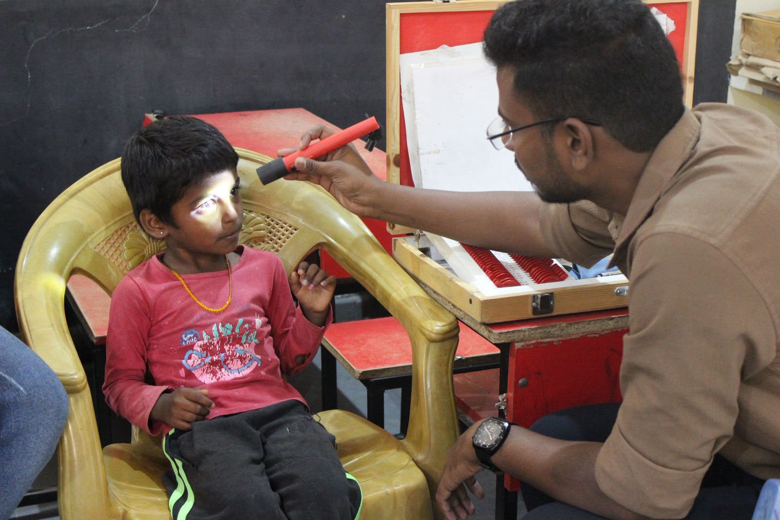 A doctor conducting a routine eye examination for a student.